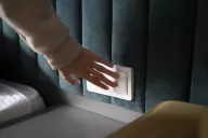 Una mano attiva senza sforzo l’interruttore della luce, portando immediatamente luminosità accendendo una lampada d’hotel.