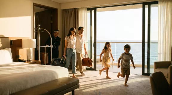 famiglia-che-entra-nella-stanza-di-un-hotel-con-valigie-in-mano